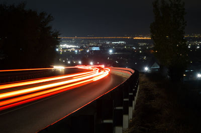 Light trails on road against sky at night