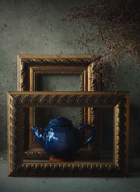 Close-up of picture frame and teapot on table