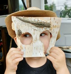 Close-up of boy playing with birch bark mask at home