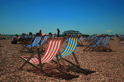 Multi colored chairs on beach against clear blue sky