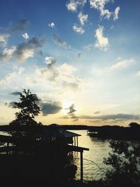 Silhouette tree by lake against sky during sunset