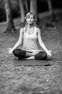 Young woman meditating in lotus position at park