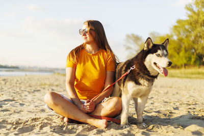 Portrait of woman with dogs on sand at beach