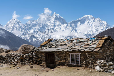 House on snowcapped mountain against sky