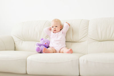 Cute baby girl sitting with toy at home