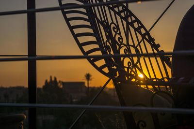 Silhouette metal railing by building against sky at sunset