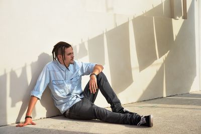 Young man sitting on floor against wall