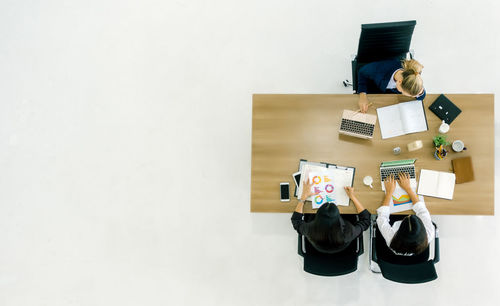 High angle view of business colleagues working together at table over white background