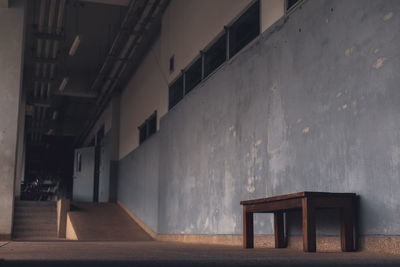 Empty bench by building corridor