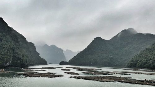 Scenic view of river by mountains against sky