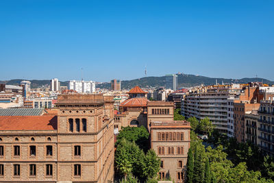 Buildings in city against clear blue sky