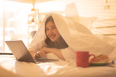 Portrait of smiling young woman lying on bed