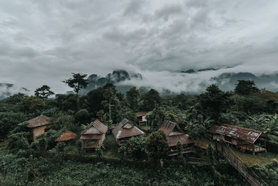 Houses and trees on field against sky