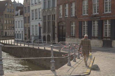 Rear view of man walking by buildings in city