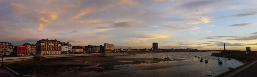 Panoramic view of sea and buildings against sky during sunset