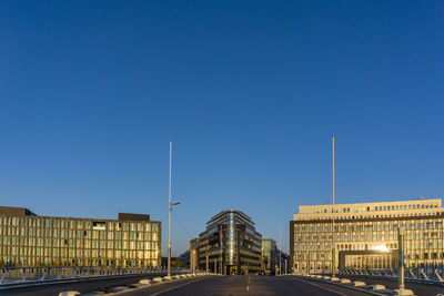 Street amidst buildings against clear blue sky