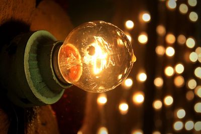 Close-up of illuminated light bulb and christmas lights