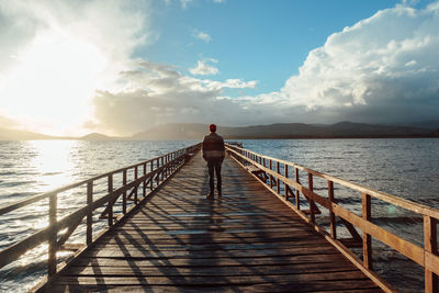 Man standing on pier over sea against sky