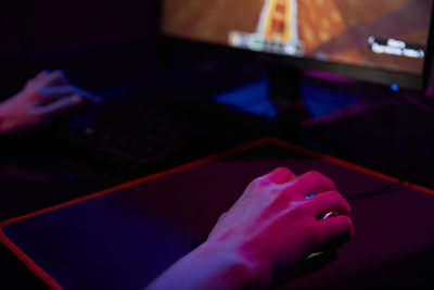 Professional gamer play computer video game in dark room, use neon colored rgb mechanical keyboard