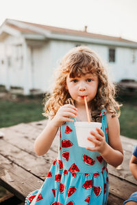 Close up of young girl drinking snow cone at table during sunset