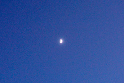 Low angle view of moon against blue sky