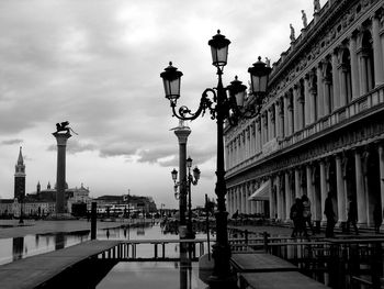 Lamp posts by historic building against sky in city