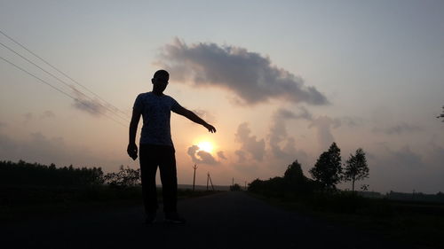 Silhouette man standing by tree against sky during sunset