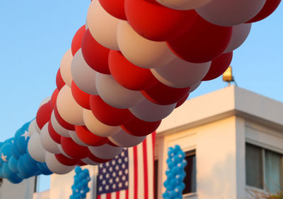 Low angle view of balloons by building with american flag