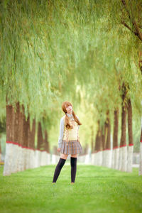 Woman standing on grass against trees