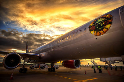 Airplane on airport runway against sky during sunset