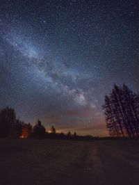 Silhouette trees on field against sky at night