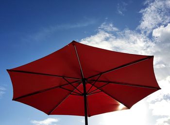 Low angle view of red beach umbrella against sky