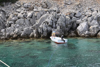 Boat sailing on sea by rocks