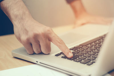 Close-up of man using laptop on table