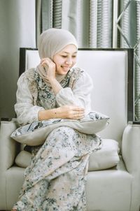 Portrait of young woman sitting on sofa at hotel 