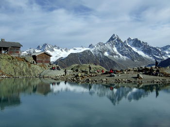 Scenic view of lake by snowcapped mountains against sky