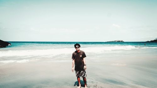 Full length of woman standing on beach against sky