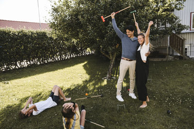 Cheerful parents playing polo with children in back yard