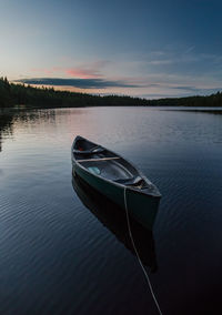 Boat moored in lake against sky during sunset