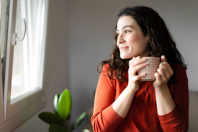 Side view of young woman using mobile phone at home