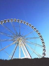 Low angle view of ferris wheel against clear blue sky