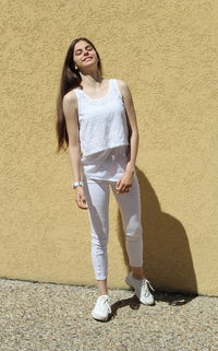 Full length portrait of woman standing against wall