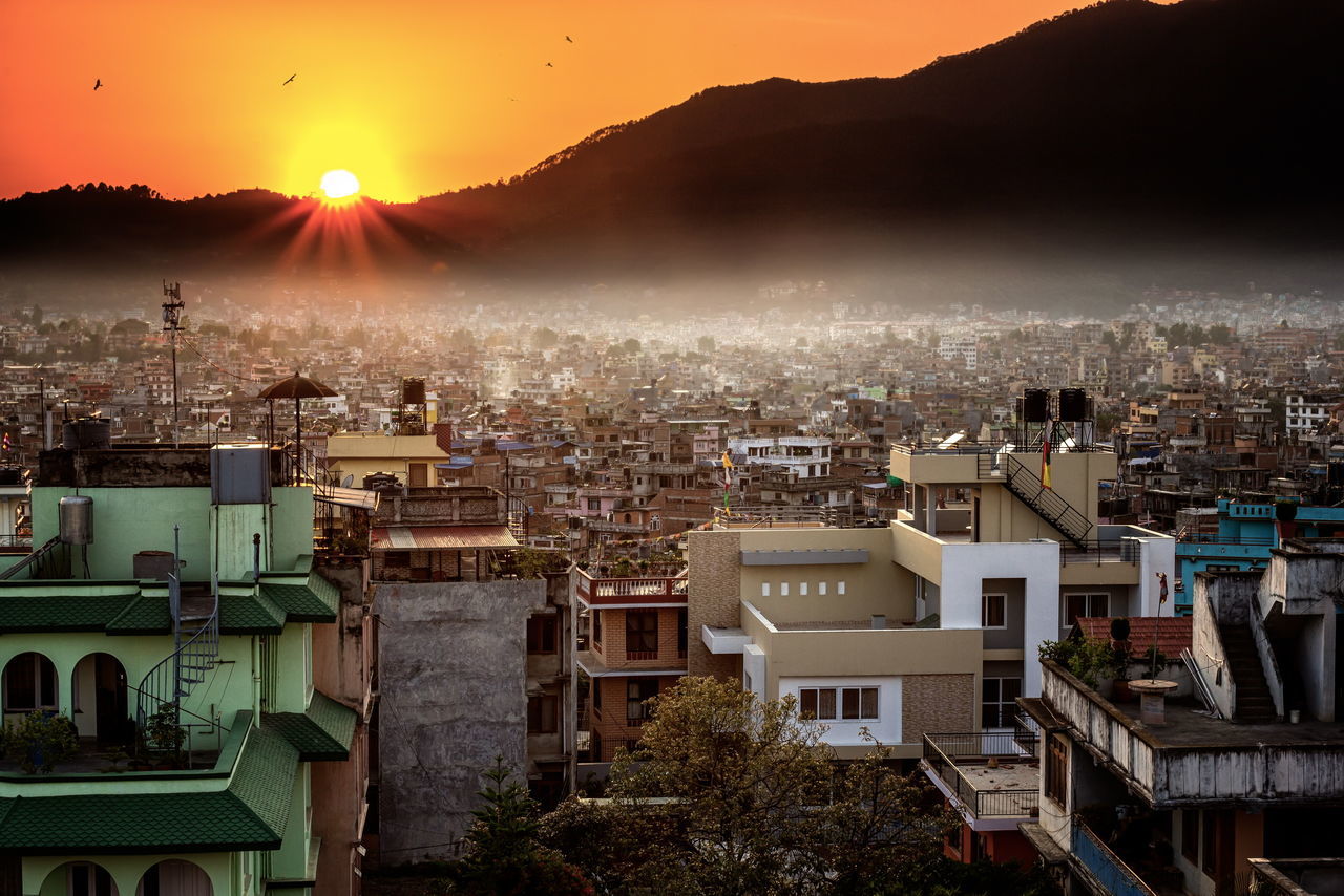 building exterior, architecture, built structure, sun, cityscape, residential district, residential building, city, house, mountain, crowded, high angle view, residential structure, sunbeam, sunlight, sunset, townscape, town, lens flare, sky