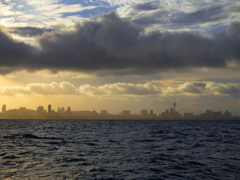 Scenic view of sea and buildings against sky during sunset