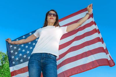 Portrait of smiling pretty young woman holding waving american flag. usa celebrate 4th of july. 