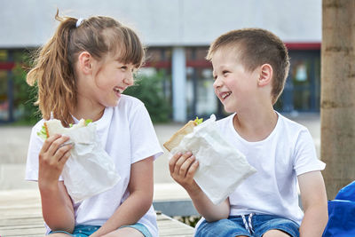 Snack during lessons. close-up portrait of happy children eating breakfast in the schoolyard. 
