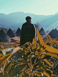 Full length of men with yellow flower and traditional village against sky