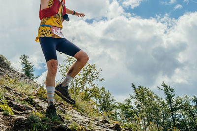 Low angle view of woman walking on rock against sky