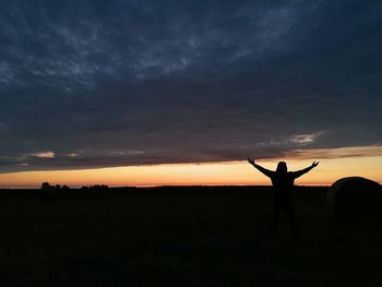 Silhouette people standing on field against sky during sunset