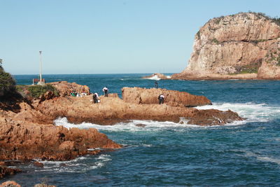 Rocks on beach against clear blue sky